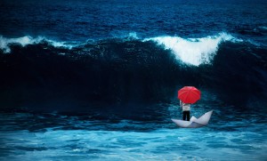 Man with red umbrella in a paperboat in the rough sea