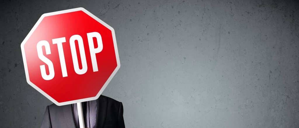 Businessman standing and holding a stop sign in front of his head
