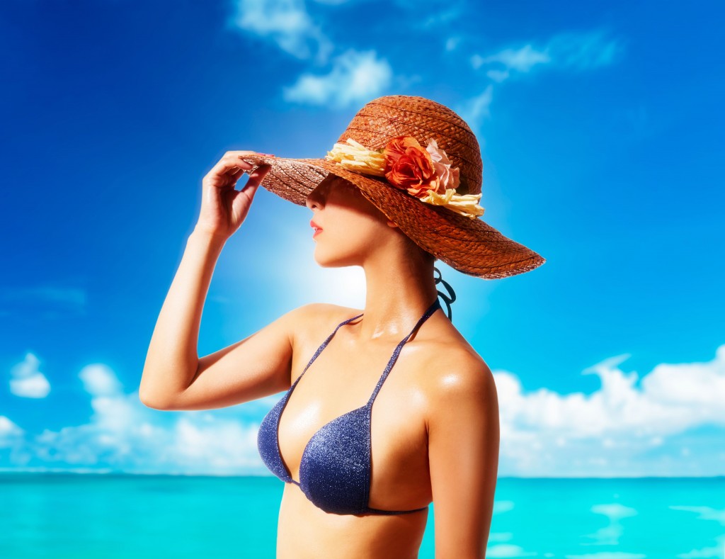 Woman with a straw hat and bikini on the beach. Summer vacation fashion style image.