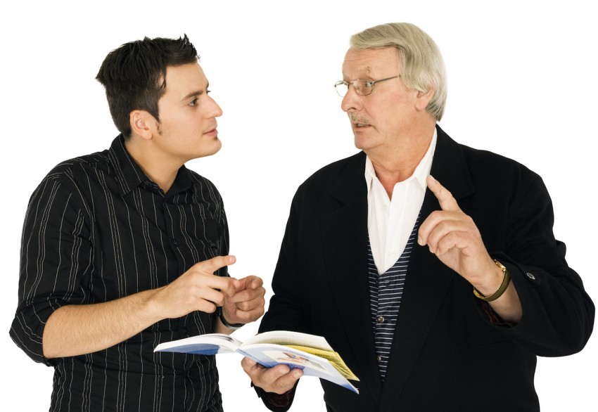View of senior man and young man gesturing and holding book