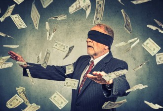 Blindfolded senior businessman trying to catch dollar bills banknotes