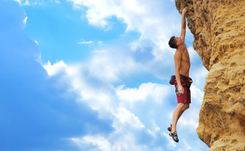 muscular guy hanging on the one hand holding rock
