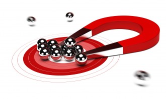 red horseshoe magnet attracting some chrome balls, white background